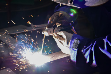 Welder is welding metal part by process shielded metal arc welding (SMAW)