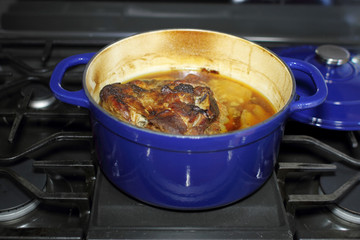 Pork roast with onions baked in a Dutch oven, resting on the stove top.