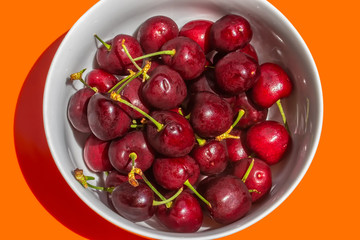 Bowl of Cherries on Orange Background