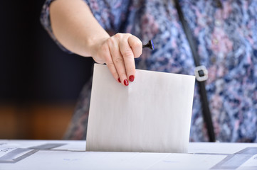 Person casting a vote into the ballot box during elections