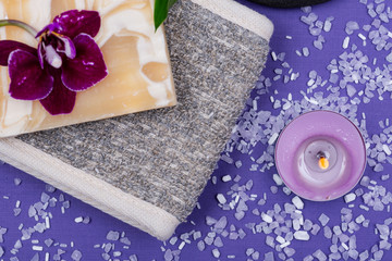 Spa Wellness Concept. Natural Back Scrubber,Goat's milk Soap, Basalt Stones, Orchid Flower, Bamboo and Lavender Tea Light Candle on purple background.