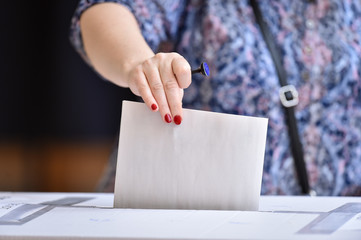 Person casting a vote into the ballot box during elections