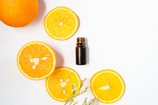Bottle of orange essential oil on white background for beauty, skin care, wellness and medicinal purposes. Flat lay.