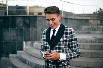 Positive handsome young student talking on smartphone.
