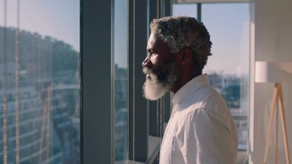 mature african american businessman looking out window planning ahead thinking of ideas for future business development with view of city at sunset 4k