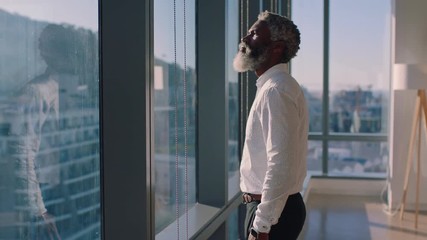 mature african american businessman looking out window planning ahead thinking of ideas for future business development with view of city at sunset 4k