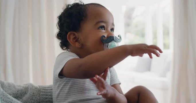 funny baby wearing moustache pacifier happy toddler sucking on dummy having fun cute infant enjoying silly humor at home 4k