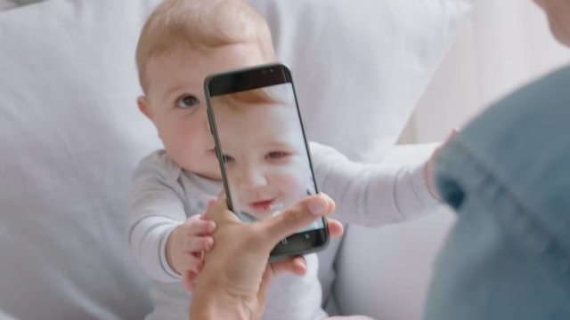 mother taking photo of baby using smartphone enjoying photographing cute toddler sharing motherhood lifestyle on social media