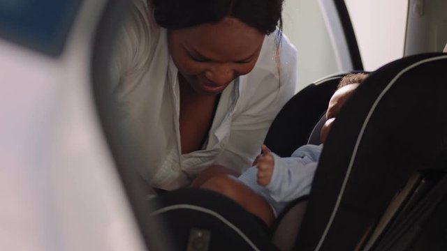 young mother putting baby in car seat securing child for road trip responsible parent caring for toddlers safety in vehicle