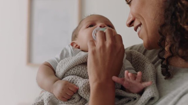 mother holding baby at home calming tired newborn gently soothing restless infant sucking on pacifier loving mom enjoying motherhood