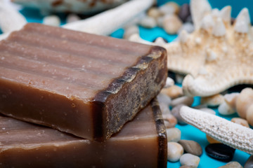 Handmade moisturizing Frankincense & Myrrh Goat's Milk Bar Soap decorated with small Pebbles, Sea Stars and Sea Shells on bright blue background.