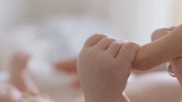 close up mother holding baby hand touching fingers nurturing newborn caring for infant enjoying motherhood connection with child