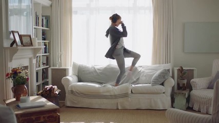 happy young woman dancing at home having fun listening to music wearing headphones enjoying weekend celebration with funky dance moves