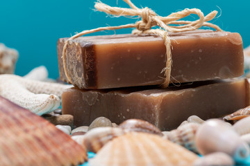 Handmade moisturizing Frankincense & Myrrh Goat's Milk Bar Soap decorated with small Pebbles, Sea Stars and Sea Shells on bright blue background.