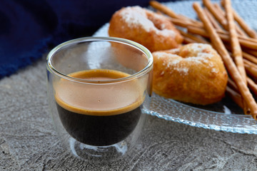 Cup of espresso on the background of the donuts on the plate and kitchen towel. Horizontal.