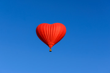 Red heart shaped balloon on the background blue sky.