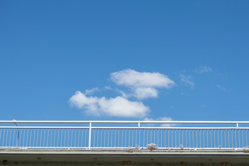 Obraz premium a handrail of a cut out bridge over a blue sky with clouds