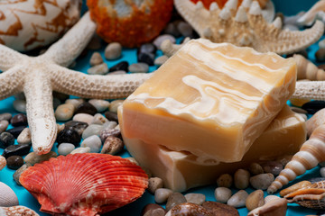 Handmade ultra-moisturizing Almond Scented Goat's Milk Bar Soap decorated with small Pebbles, Sea Stars and Sea Shells on bright blue background.