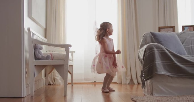 cute little girl dancing playfully pretending to be ballerina happy child having fun playing dress up wearing ballet costume with fairy wings at home 4k