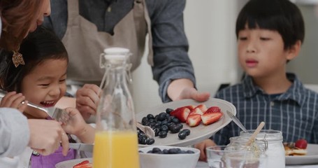 happy asian family eating pancakes for breakfast children enjoying healthy homemade meal with parents on weekend morning in kitchen 4k footage - Powered by Adobe