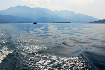 Sea and mountains in the evening light. A lone ship on the horizon