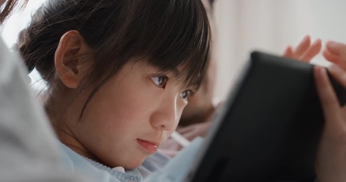 little asian girl using tablet computer watching entertainment with parents playing game on touchscreen device browsing online relaxing on sofa together at home 4k 