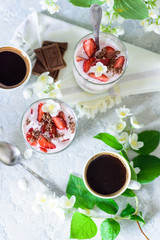 Curd dessert with strawberries and chocolate on the background of flowers and coffee top view
