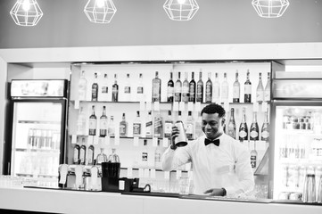 Naklejka na ściany i meble African american bartender at bar with shaker. Alcoholic beverage preparation.