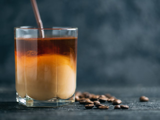 Cold coffee in a glass on a dark wooden table with copyspace