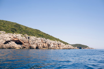 Fototapeta premium Seascape of the Adriatic Sea. The sea with mountains and mountains in the background. Boat sailing on the sea. Italy, Montenegro, Adriatic tourism