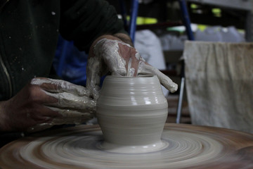 a craftsman with 13 years of experience unscrews a cylinder on a potter's wheel - the fundamental form of any ceramic product and fingers shaped it a pot. correct hand setting.