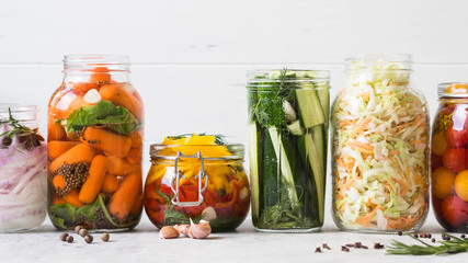 Pickled vegetables. Salting various vegetables in glass jars for long-term storage. Preserves vegetables in glass jars. Variety fermented green vegetables on table.