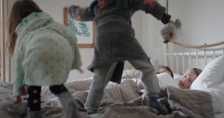 happy children jumping on bed waking up mother and father enjoying playful morning with kids - Powered by Adobe