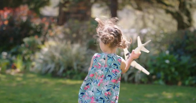 little girl playing with toy airplane happy child playing game running imagining travel freedom having fun outdoors in sunny park enjoying childhood 4k 