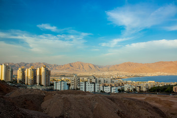 Israeli city Eilat photography foreshortening from above in high outskirts mountain view point with living building and Gulf of Aqaba Red sea bay place in sun rise early morning time 