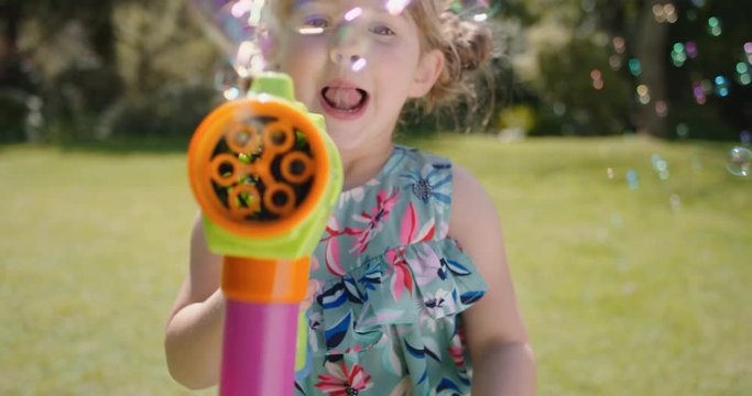 happy little girl blowing soap bubbles playing in sunny garden running with toy gun enjoying fun game funny playful child enjoying summer 4k