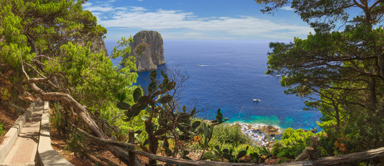 Panoramic view of famous Faraglioni Rocks, most visited travel attraction of Capri Island, Italy. Beautiful paradise landscape with azure sea in summer sunny day.