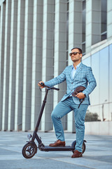 Cheerful modern man is driving his electro scooter near his office after long hard day.