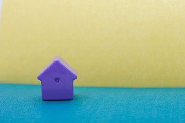 Fototapeta na wymiar little lilac plastic house on the field/ blue and yellow felt bachground