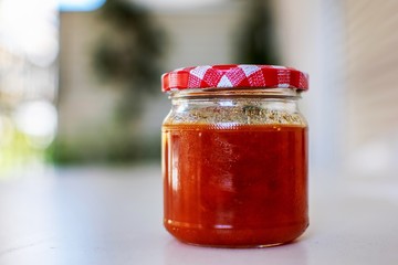 Jar with apricot jam placed on a table.Nice soft background.
