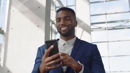 young african american businessman using smartphone texting walking in corporate office building checking email messages online successful male executive at work 4k - Powered by Adobe