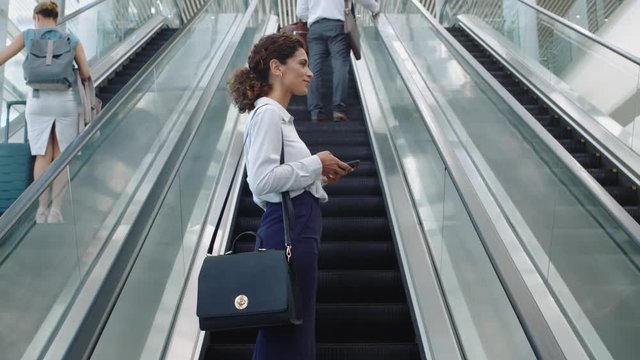 mixed race business woman using smartphone browsing online female commuter on escalator traveling for business trip walking in office metro lobby 4k