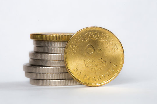 50 piaster Egyptian coin in-front of stack of Egyptian coins isolated on a white-background 