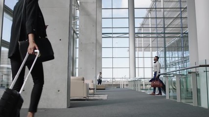 diverse people at busy airport pulling trolley bags arriving and departing terminal tourists travelling international walking in lobby with luggage on the move 4k footage - Powered by Adobe