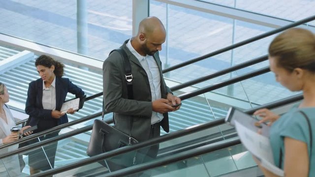 mixed race businessman using smartphone on escalator texting checking email messages online successful male executive arriving at work in corporate office building 4k