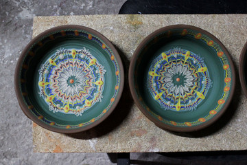 large plates decorates a clay plate made on a pottery wheel using colored engobes. National method Bulgarian flyandrovka.