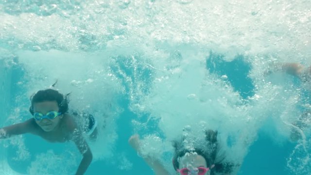 happy children jumping in swimming pool splashing underwater playfully having fun together on sunny day enjoying summer vacation 4k