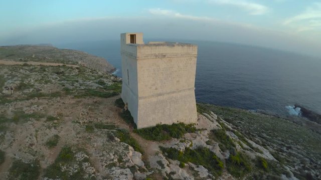 Drone shot of stone tower with sea in the background