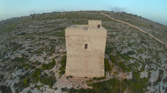 Drone shot of stone tower with sea in the background