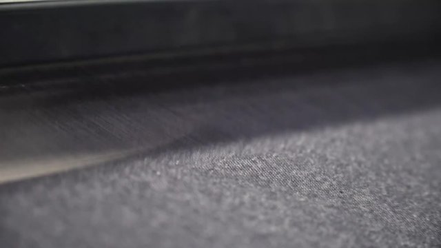 Stunning closeup static shot of denim being woven from an automated machine.